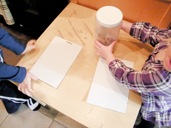 Two toddlers with canister of rocks preparing to do their rock sculpture art.