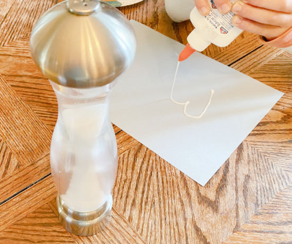 Child drawing hearts on their paper with glue bottle.