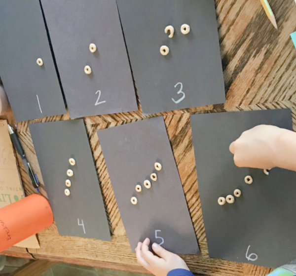 black construction paper is cut in half and labeled with number symbols and words for a preschool counting practice activity.
