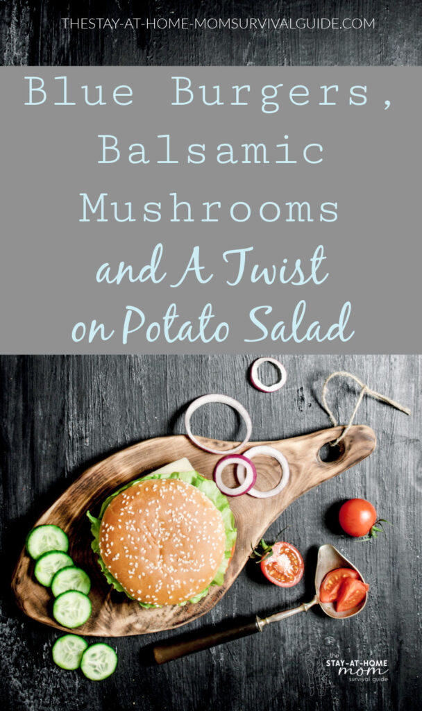 Hamburger with sesame seed bun sitting on wooden board with slices of onion and pieces of tomato around it. Text reads blue burgers, balsamic mushrooms and a twist on potato salad.