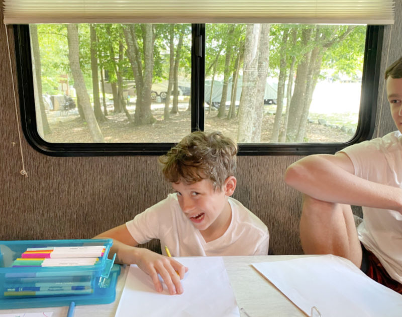 Child seated at table in RV camper road schooling with MasterBooks curriculum.