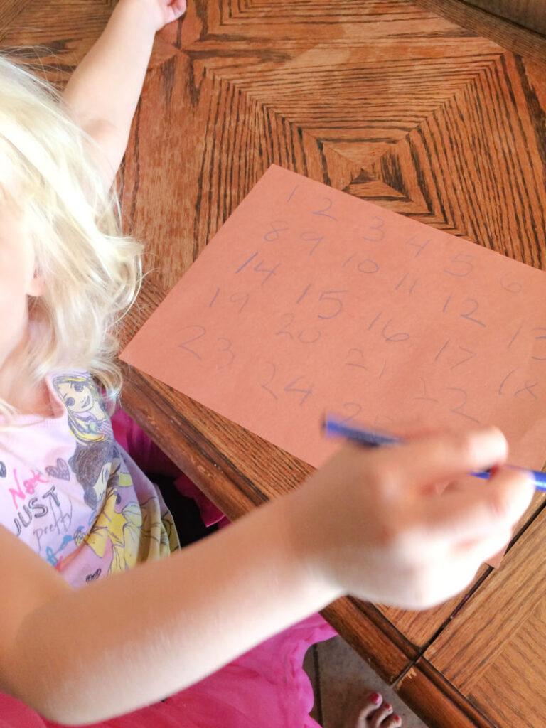 Preschooler writing numbers with guidance on paper.