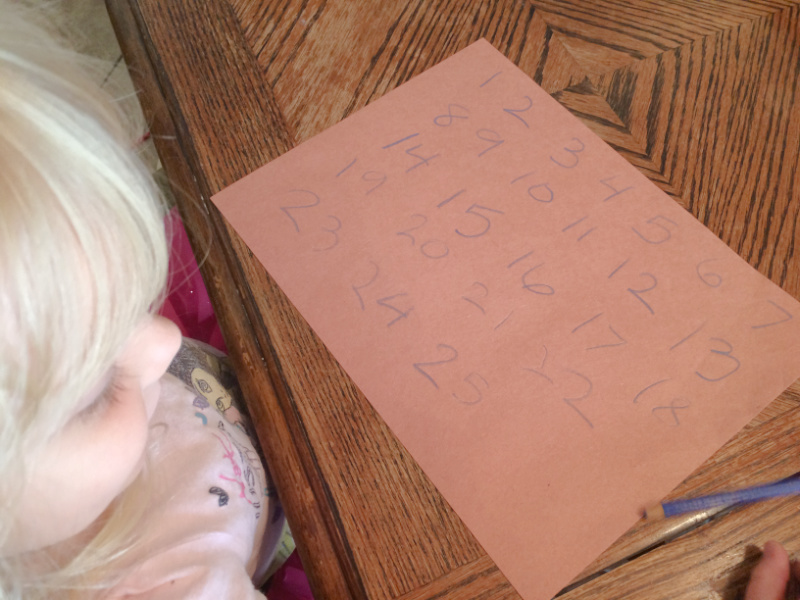 Preschooler writing two-digit numbers to learn how to write numbers and counting skills.