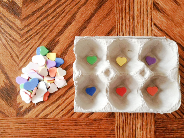Egg carton sticker and color sorting activity set up on a table with prepared egg carton with stickers and a pile of stickers to use as sorting pieces.