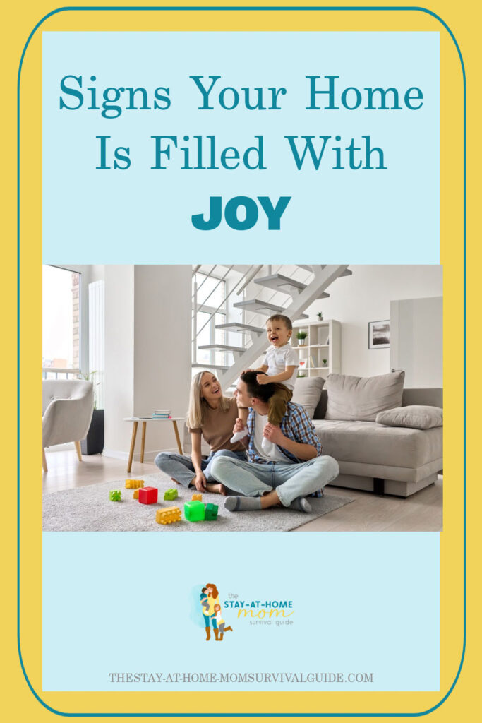 Mother, father and toddler playing on tge floor together. Toys are cluttered about. Text reads signs your home is filled with joy.