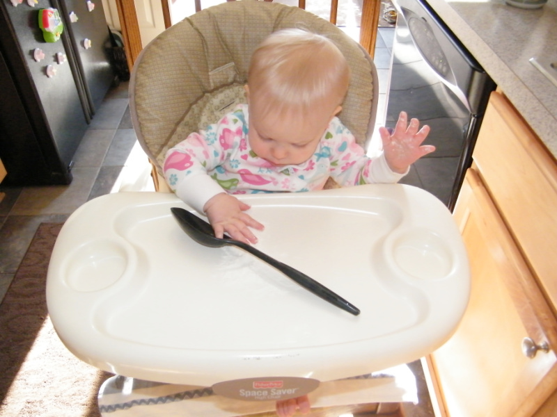 Baby in high chair playing with flour as a sensory activity.