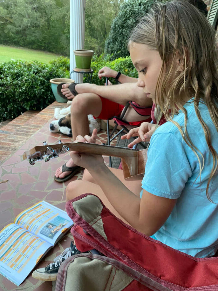 Girl playing ukelele on the porch during a power outage.