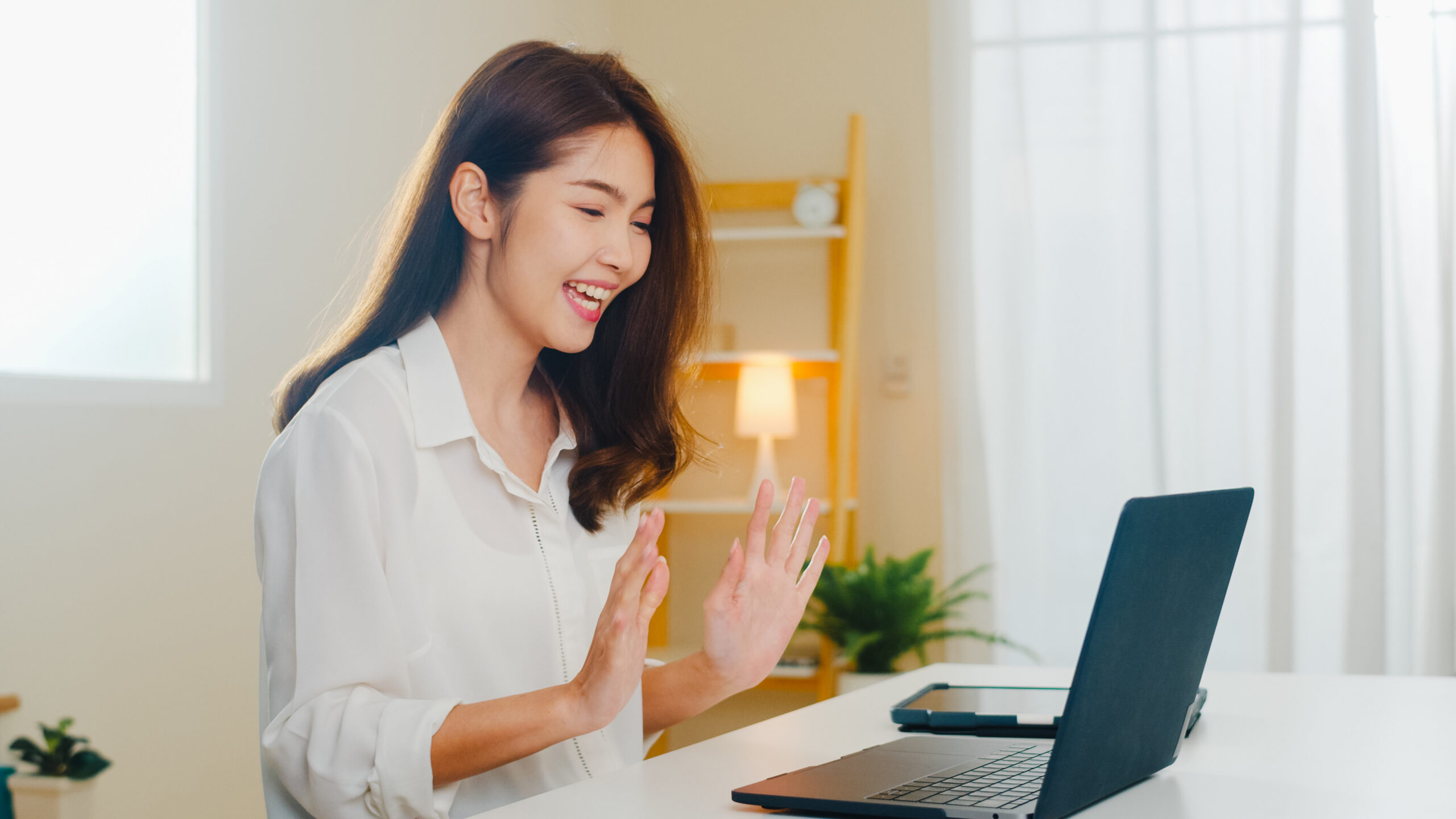 Young Asian business female using laptop video call talking with couple while working from home at living room.